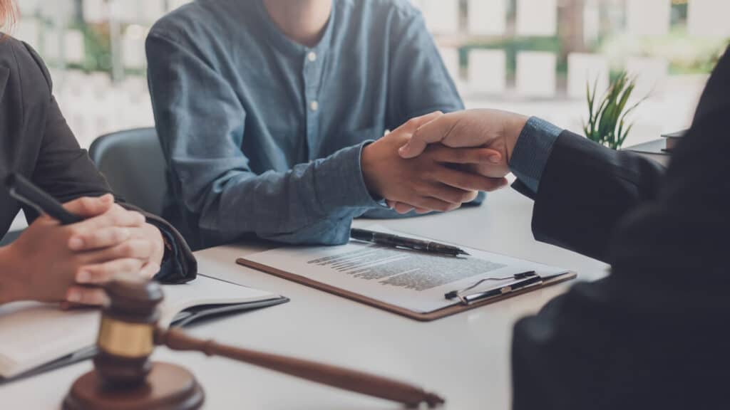 Lawyer shaking hands with someone after signing documents.